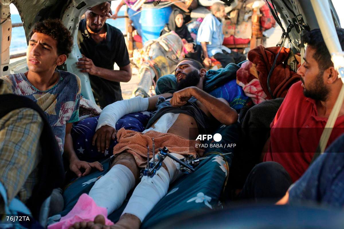 A wounded man lies in a vehicles as displaced Palestinians move with their belongings southwards on a road in the Nuseirat refugee camp area in the central Gaza Strip on September 23, 2025, as Israel presses its ground offensive to capture Gaza City amidst the war against Hamas. - AFP