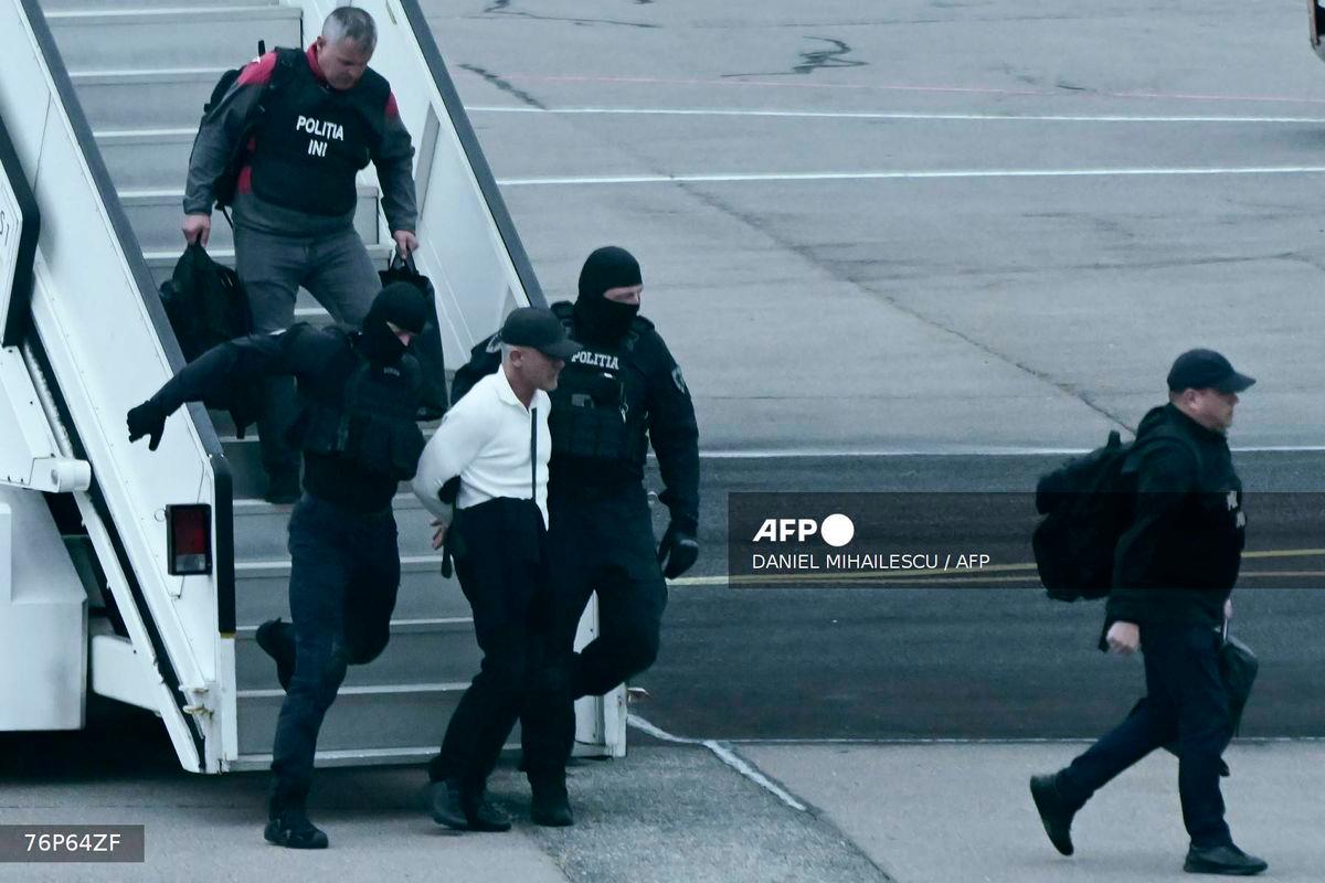 Masked police officers escort Moldovan oligarch Vladimir Plahotniuc (C), accused of acting of behalf of Russia, as they disembark an aircraft after his extradition from Greece following his arrest earlier in July, at Chisinau International Airport, on September 25, 2025. (Photo by Daniel MIHAILESCU / AFP)