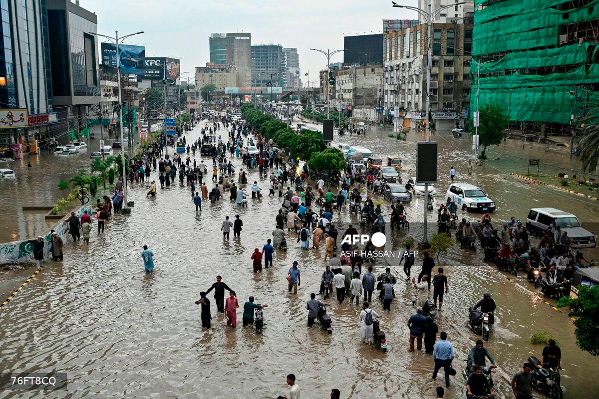 (FILES) People wade through a flooded street after heavy rainfall in Karachi on August 19, 2025. - AFP