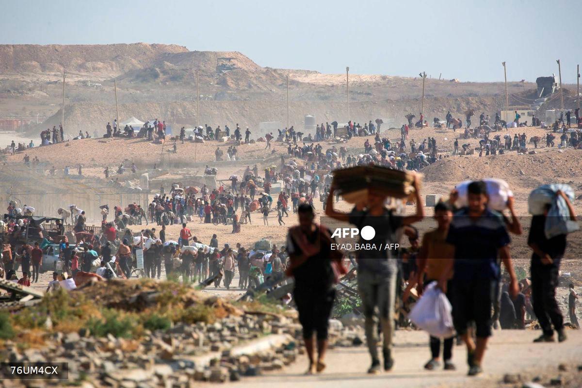 People walk with bags of humanitarian aid they received at a distribution centre run by the US and Israeli-backed Gaza Humanitarian Foundation (GHF), at the so-called Netzarim corridor, in Nuseirat in the central Gaza Strip, on September 26, 2025. - AFP