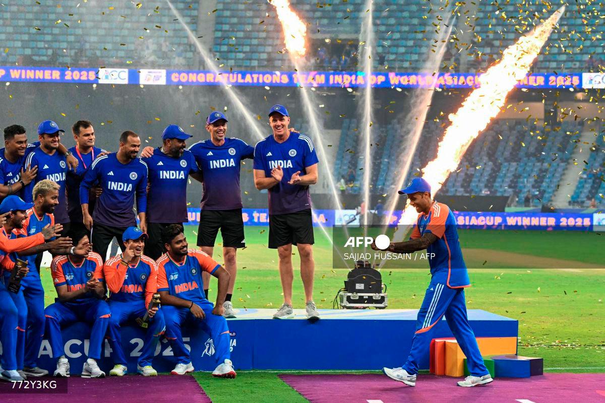 India's captain Suryakumar Yadav (R) playfully pretends to hold the trophy as his team celebrates their victory at the end of the Asia Cup 2025 Twenty20 international cricket final match between India and Pakistan at the Dubai International Stadium in Dubai on September 28, 2025. - AFP
