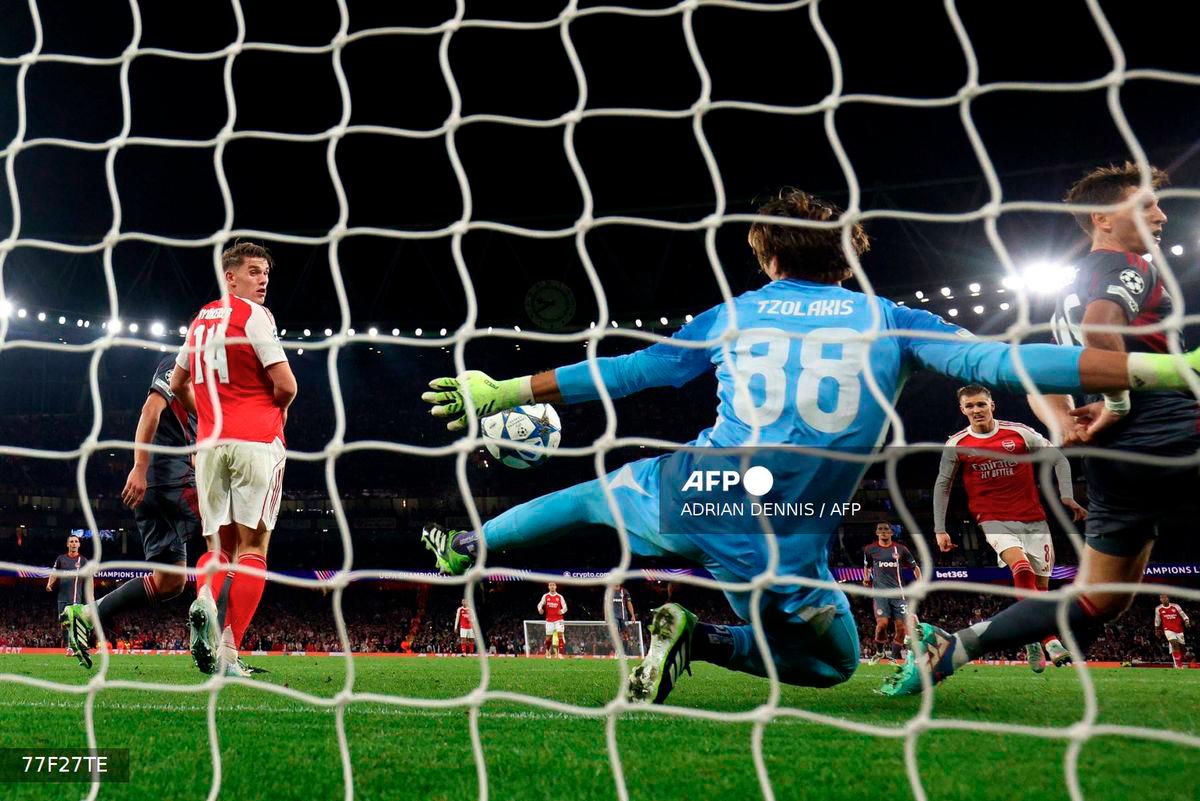 Olympiakos' Greek goalkeeper #88 Konstantinos Tzolakis reaches to save a shot from Arsenal's Norwegian midfielder #08 Martin Odegaard during the UEFA Champions League, league phase football match between Arsenal and Olympiacos at the Emirates Stadium in north London on October 1, 2025. - AFP