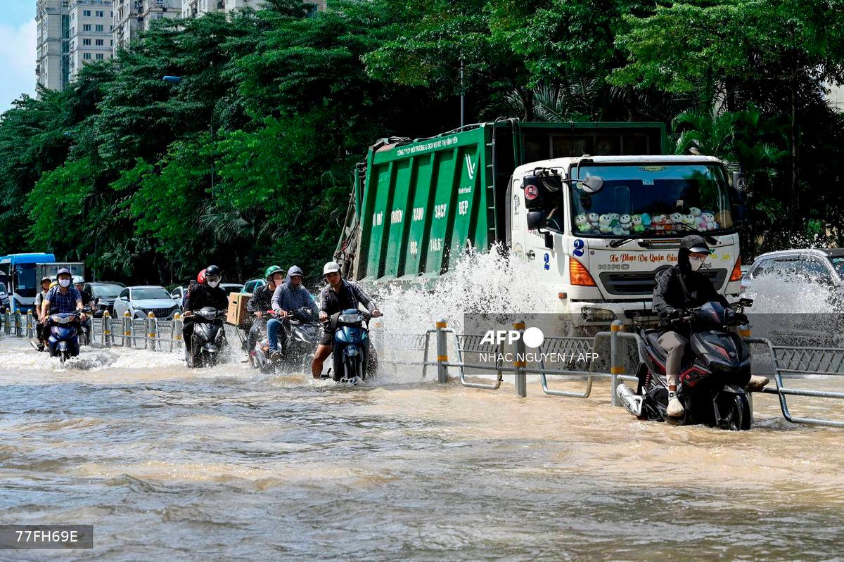 Motorcyclists and vehicles drive on a flooded street in Hanoi on October 2, 2025. Persistent heavy rain in the days after Typhoon Bualoi landed in Vietnam has brought widespread flooding to the capital Hanoi. - AFP