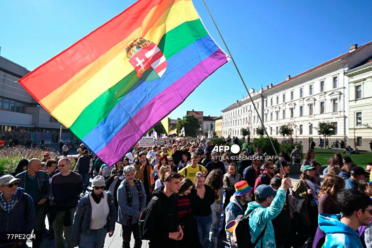 A participant holds a rainbow flag with the Hungarian crest during a pride march in Pecs, south-western Hungary, on October 4, 2025. - AFP