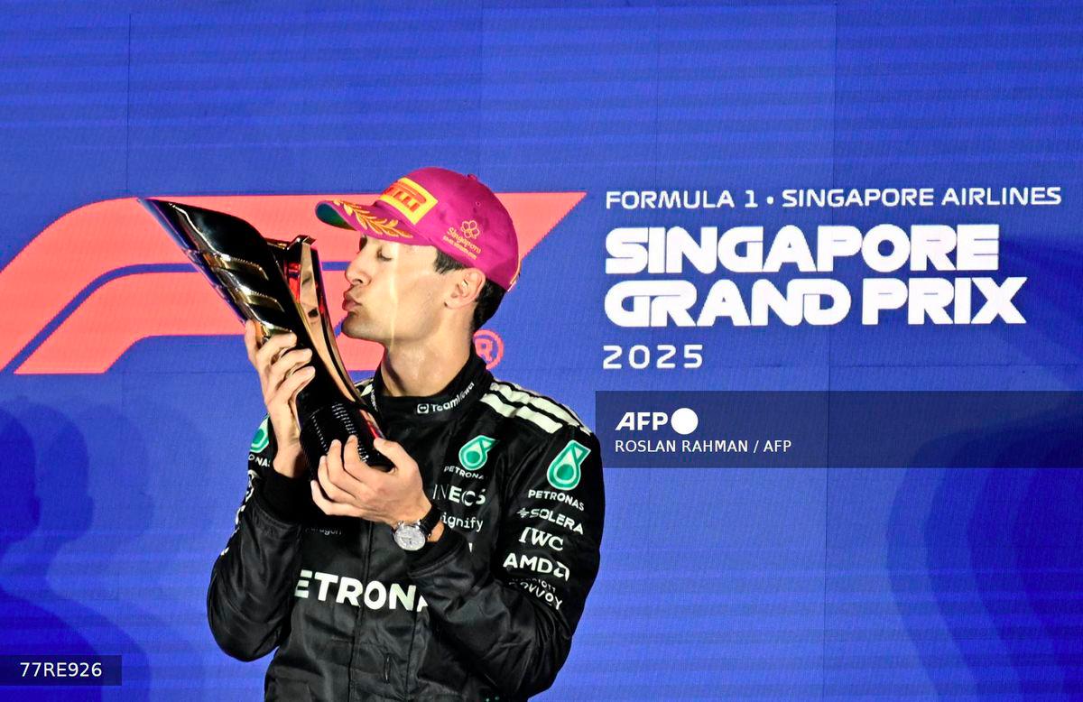 First-placed Mercedes' British driver George Russell celebrates on the podium after the Formula One Singapore Grand Prix night race at the Marina Bay Street Circuit in Singapore on October 5, 2025. - AFP