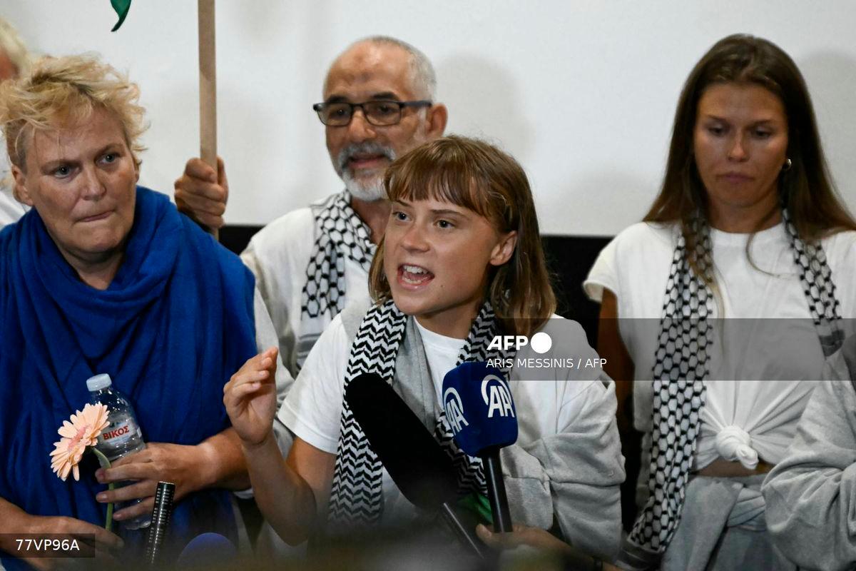 Swedish climate campaigner Greta Thunberg (C) delivers remarks upon arrival alongside activists who were sailing aboard vessels from the Gaza-bound aid flotilla before being stopped and detained by Israeli forces, greeted by a crowd of supporters, at the arrivals area of Athens International Airport on October 6, 2025. (Photo by Aris MESSINIS / AFP)
