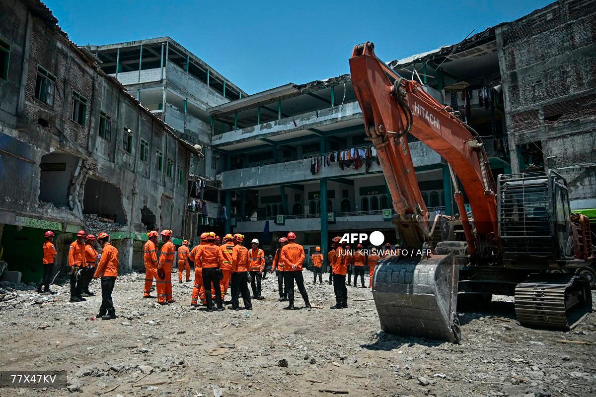 Rescue team members from the National Search and Rescue Agency (BASARNAS) gather after a closing ceremony marking the end of debris removal and search operations at the site of the collapsed Al Khoziny Islamic boarding school in Sidoarjo, East Java, on October 7, 2025. - JUNI KRISWANTO / AFP
