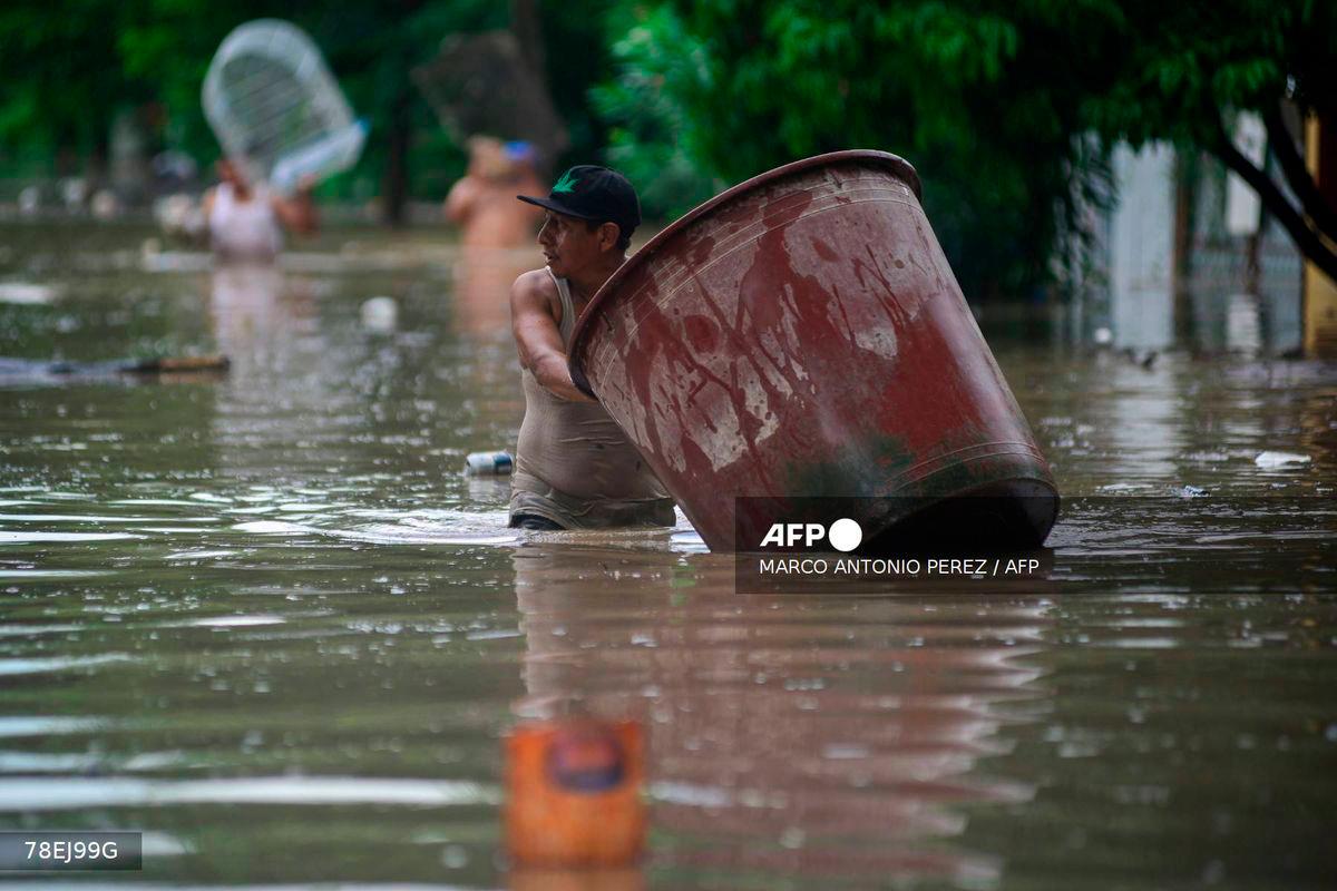 A man wades through a flooded street after heavy rains in Poza Rica, Veracruz state, Mexico on October 10, 2025. - AFP