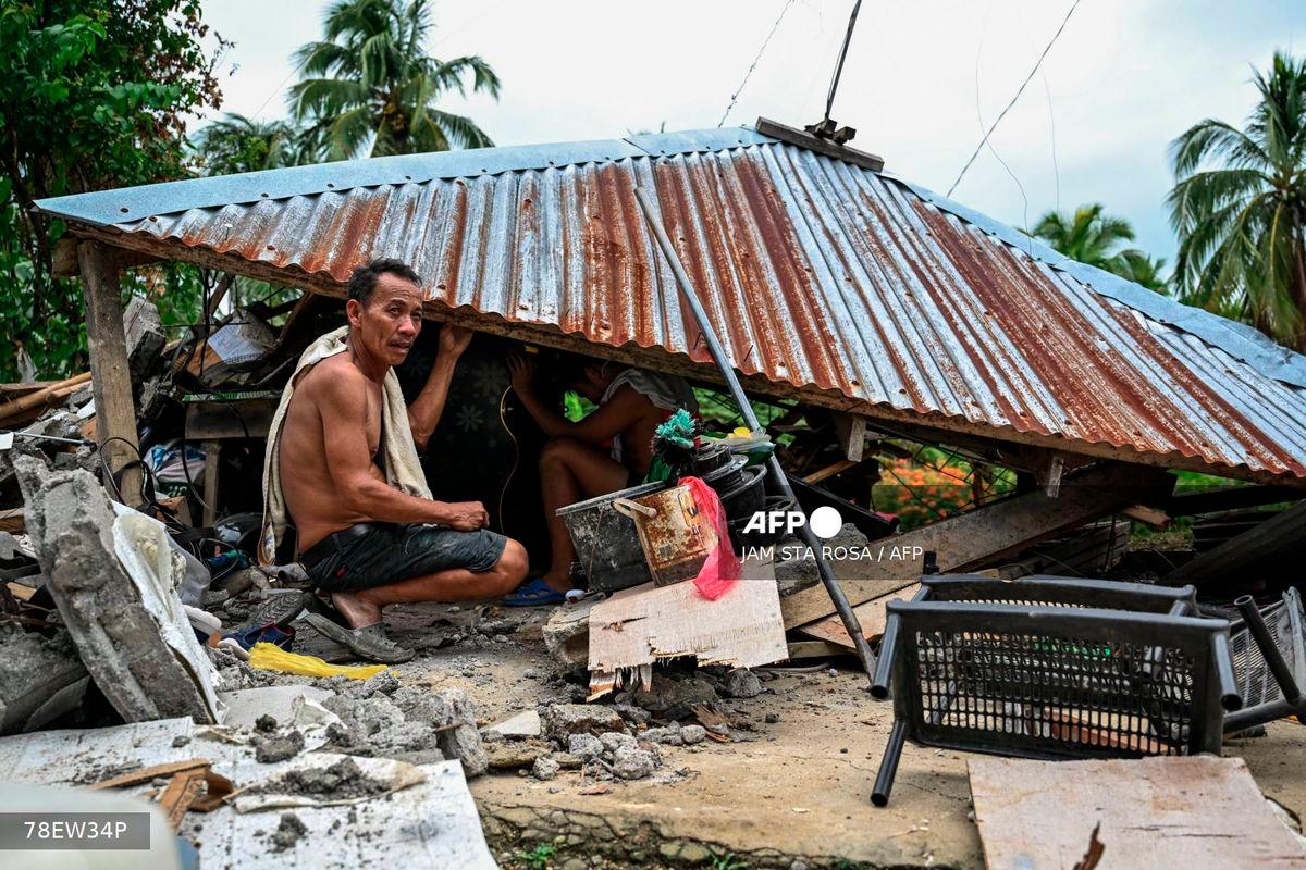 Men look for items in a collapsed house in Manay, in the province of Davao Oriental on October 11, 2025, after two powerful quakes struck off the southern Philippines on October 10, killing at least eight people and triggering tsunami warnings. - AFP
