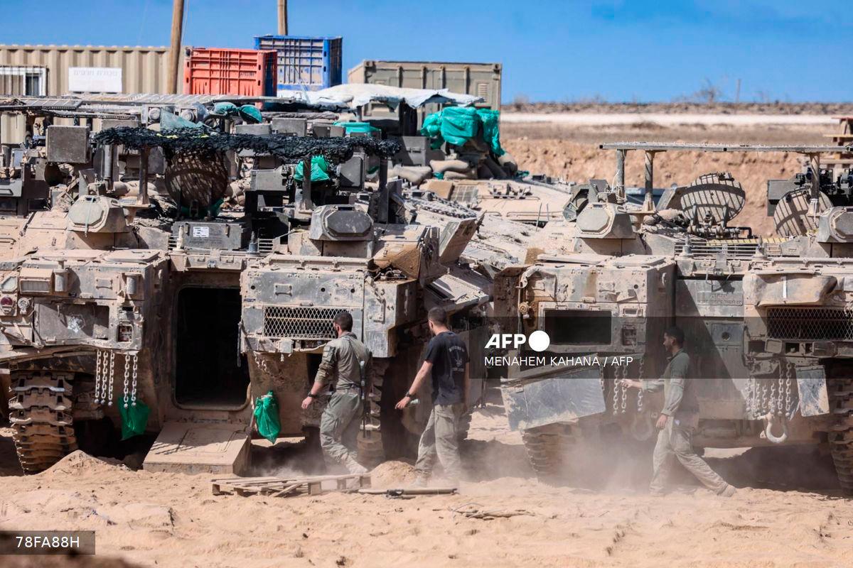 Israeli soldiers carry out maintenance on tanks positioned in southern Israel, on the border with the Gaza Strip on October 11, 2025. - AFP
