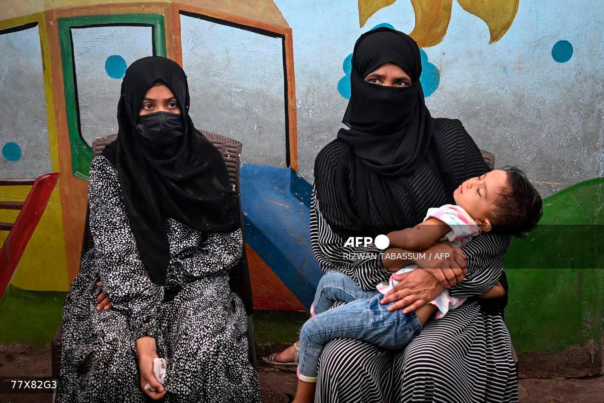 In this photograph taken on July 31, 2025, Amina (L), a household helper, sits beside her mother as she speaks during an interview with AFP in Karachi. Photo by RIZWAN TABASSUM / AFP