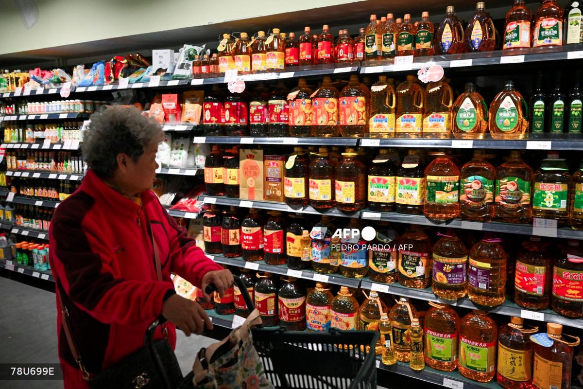 A shopper browses past shelves of cooking oil for sale at a supermarket in Beijing on October 15, 2025. - AFPPIX