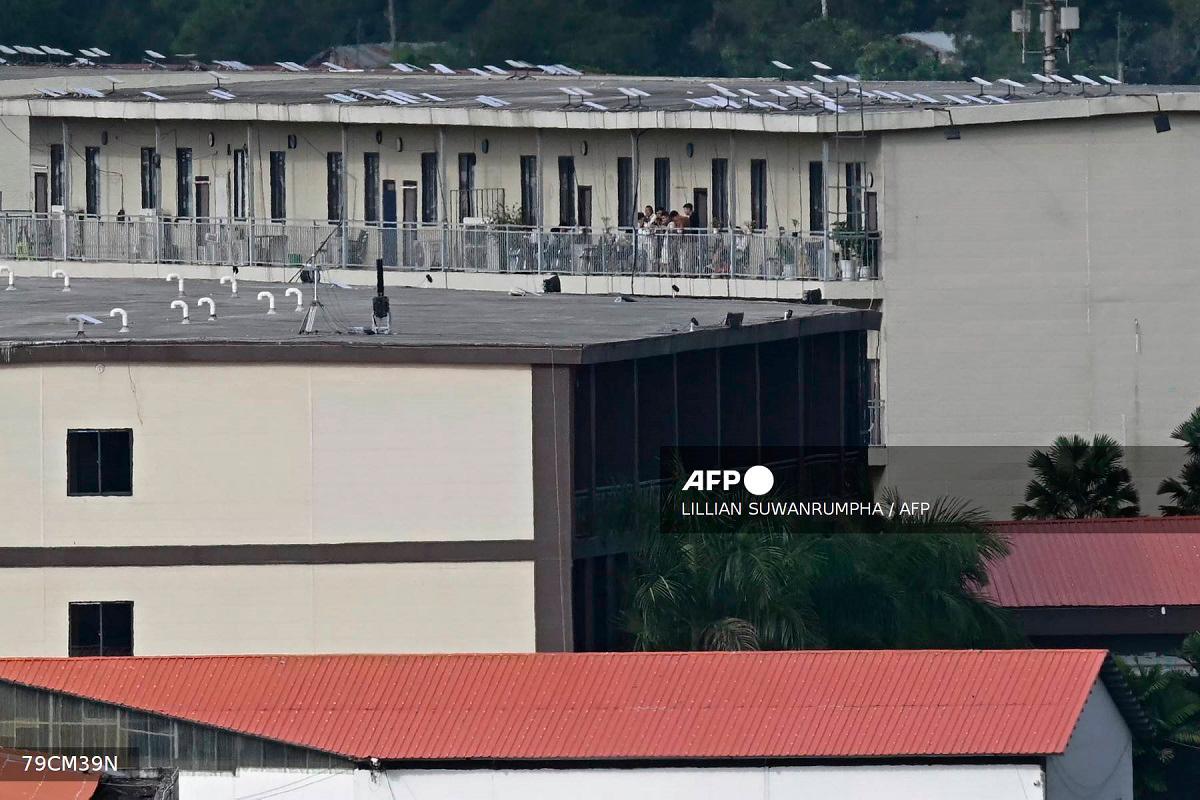 (FILES) This photo taken on September 17, 2025 shows people on a balcony of a building with what appears to be Starlink satellite dishes on the roof in the KK Park complex in Myanmar’s eastern Myawaddy township, as pictured from Mae Sot district in Thailand’s border province of Tak. - Lillian SUWANRUMPHA / AFP