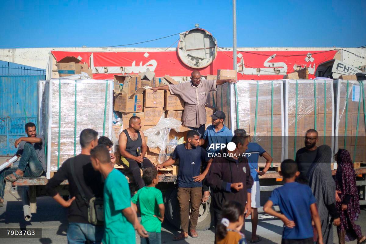 Displaced Palestinians gather around a truck to receive aid supplies that entered Gaza in the morning at the Nuseirat refugee camp in the central Gaza Strip, on October 20, 2025. (Photo by Eyad BABA / AFP)
