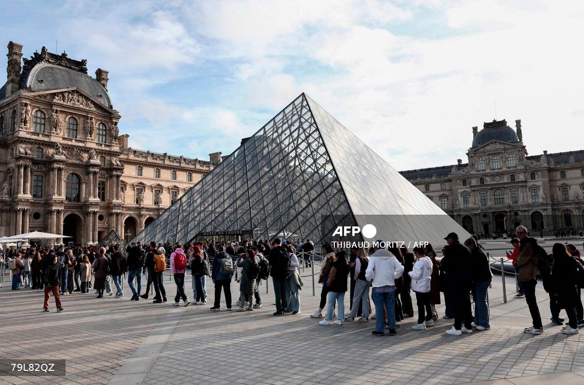 Visitors queue in front of the Pyramide du Louvre, designed by Chinese-US architect Ieoh Ming Pei, with the Louvre Museum in the background in Paris on October 22, 2025. - Thibaud MORITZ / AFP