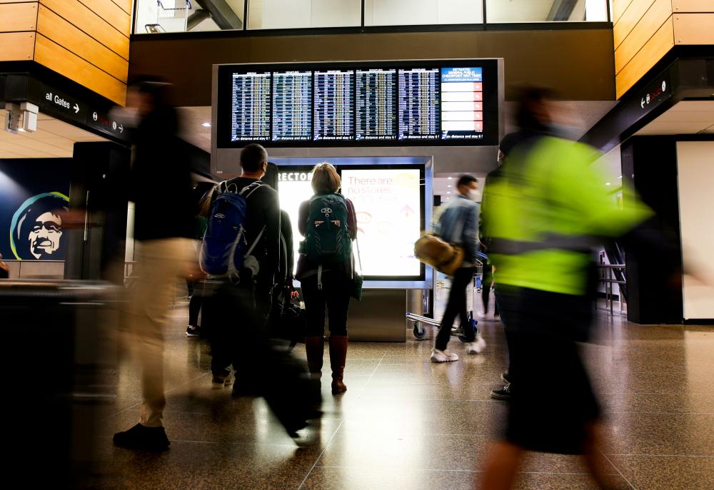 FILE PHOTO: Travellers check a departures list at the ticketing level of Seattle-Tacoma International Airport before the Thanksgiving holiday in Seattle, Washington, U.S. November 24, 2021. REUTERSpix