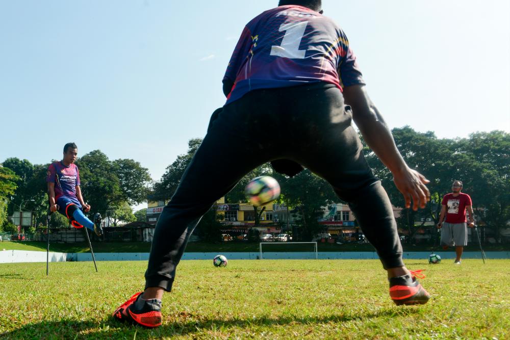 $!3. Haqimie (left) practicing his football skills with the Kuala Lumpur Amputee Football team.