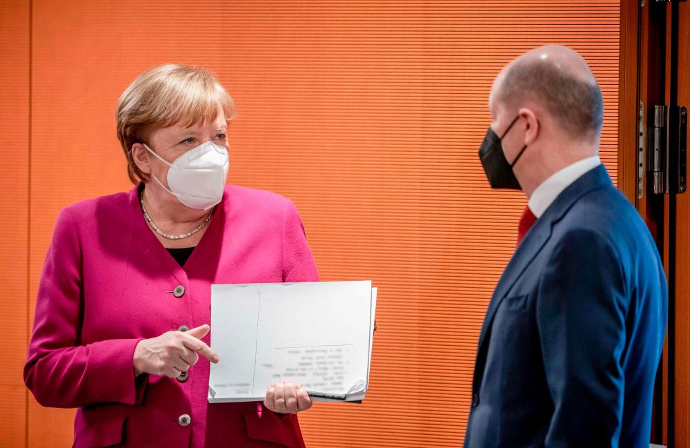 Merkel and Scholz arriving for the weekly cabinet meeting at the Chancellery in Berlin today. – AFPPIX