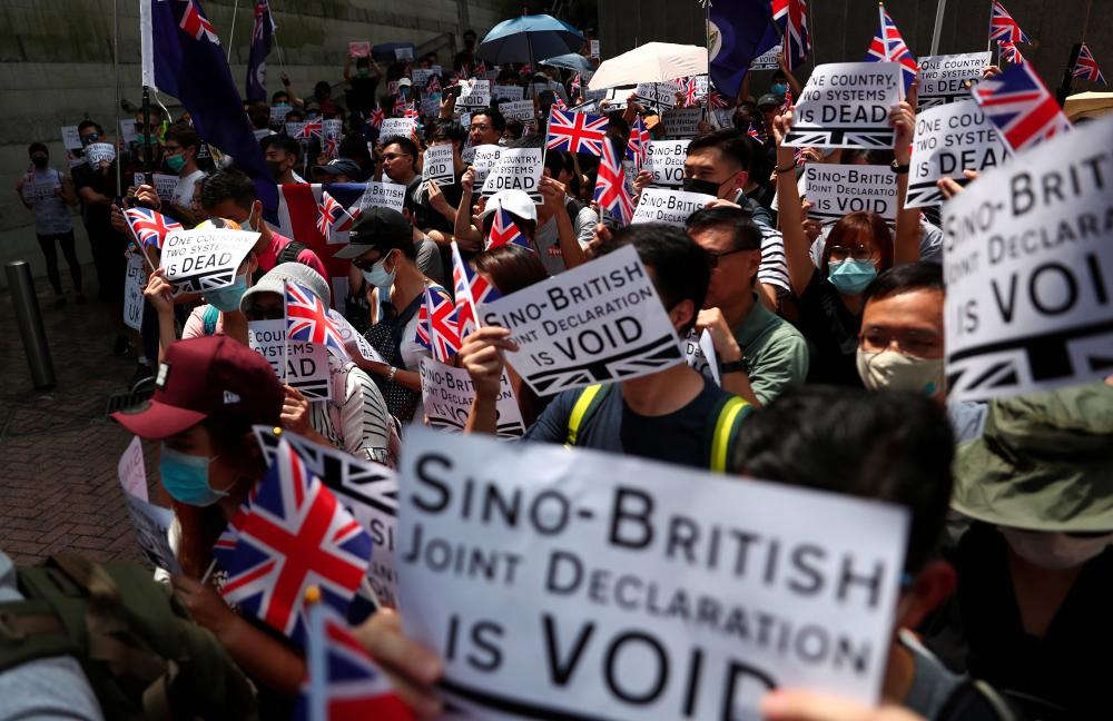 Anti-government protesters hold up banners, placards, Union Jack flags as they gather at the British consulate General in Hong Kong, China, Sept 15, 2019. - Reuters