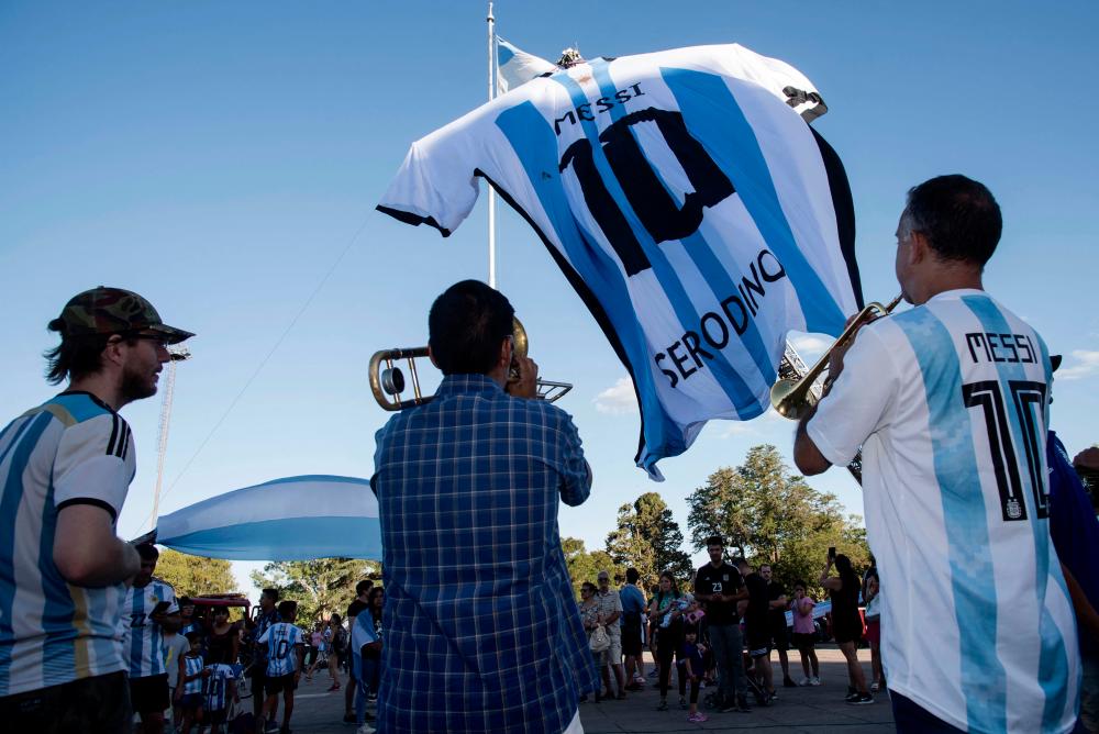 Fans look at a giant jersey of Argentine forward Lionel Messi displayed in Rosario, Argentina, on December 15, 2022, on the eve of the Qatar 2022 World Cup final football match between Argentina and France. AFPPIX