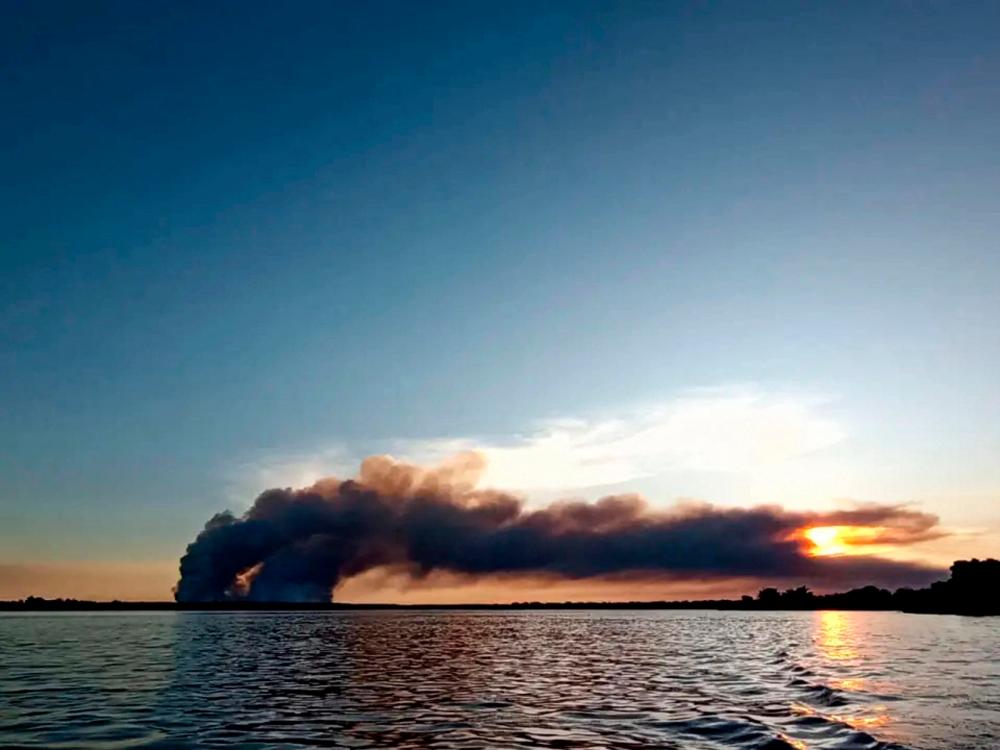 This handout picture released by Telam shows black smoke rising from a fire at a forest plantation in Ituzaingo, Corrientes province, Argentina on March 13, 2023. AFPPIX