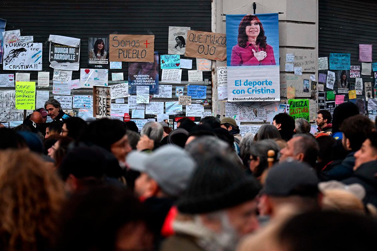 People gather past a wall with messages in support of former Argentine President Cristina Fernandez de Kirchner outside her residence in Buenos Aires on June 17, 2025. On June 17, 2025, a judge agreed to let Argentine ex-president Cristina Kirchner to serve a six-year fraud sentence at home, easing concern among backers keeping a vigil outside her apartment with plans to protest in case she was jailed. - Luis ROBAYO / AFP
