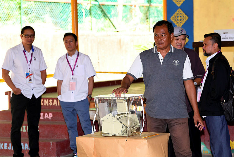 Election Commission Chairman Azhar Azizan Harun (second left, behind) and his deputy Dr Azmi Sharom (left, behind) watch as a voter casts his ballot during the Sandakan by-election, at SK Tanjung Papat 1&amp;2, on May 11, 2019. — Bernama