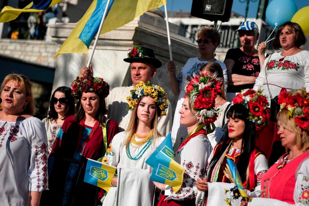 Ukrainian wearing traditional embroidered clothing listen to their national anthem as they take part in the celebration of Vyshyvanka Day, an annual celebration of Ukrainian folk traditions, in the streets of Athens on May 22, 2022. AFPpix