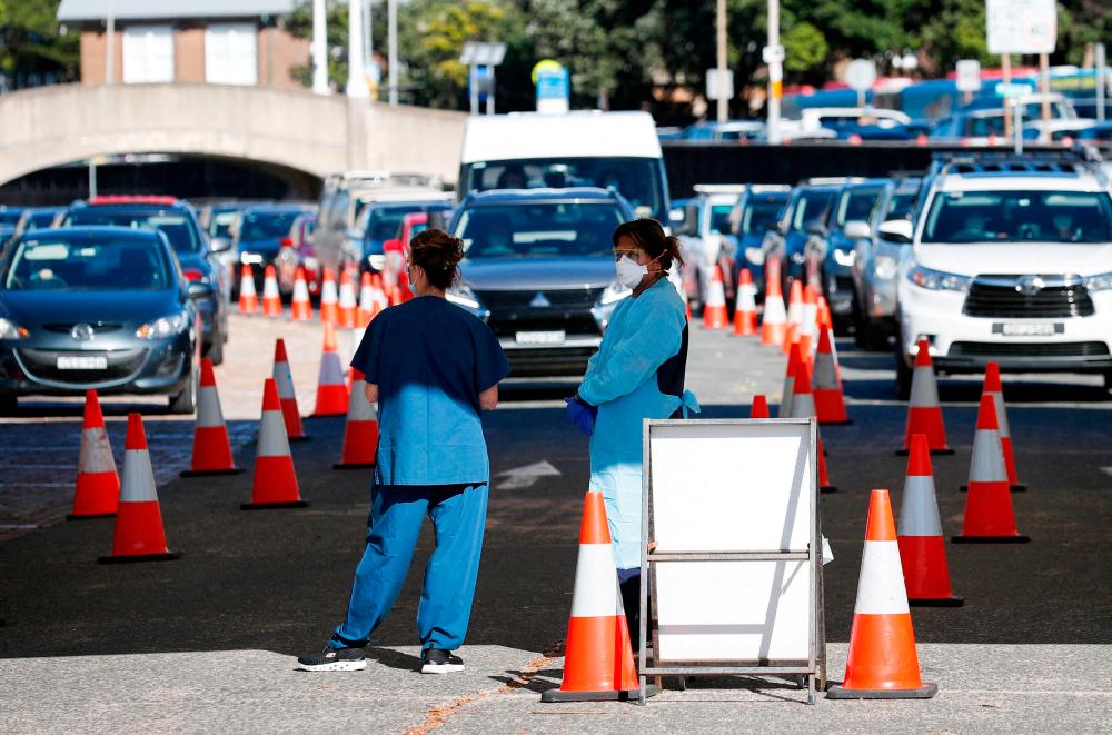FILE PHOTO: Healthcare workers wait for the next vehicle at a coronavirus disease (Covid-19) testing clinic as the Omicron coronavirus variant continues to spread in Sydney, Australia, December 30, 2021. REUTERSpix