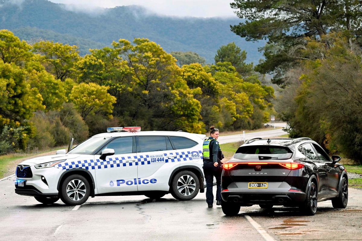 Police divert traffic at a road block to a property as the search intensifies for a fugitive linked to the murder of two police officers in Porepunkah on August 27, 2025. Police searched the Australian bush on August 27, for a heavily armed 56-year-old gunman still on the run a day after allegedly killing two officers and wounding a third. (Photo by William WEST / AFP)