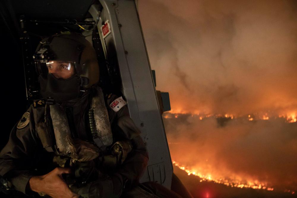 This handout photo taken on December 21, 2019 and obtained on December 22 from the Australia Department of Defence shows an aircrewman monitoring the Tianjara fire from a helicopter in the Moreton and Jerrawangala National Park in Moreton. - AFP