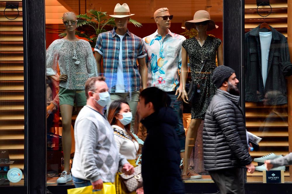 Pedestrians, some wearing face masks, walk through Sydney’s central business district on August 12, 2020. — AFP