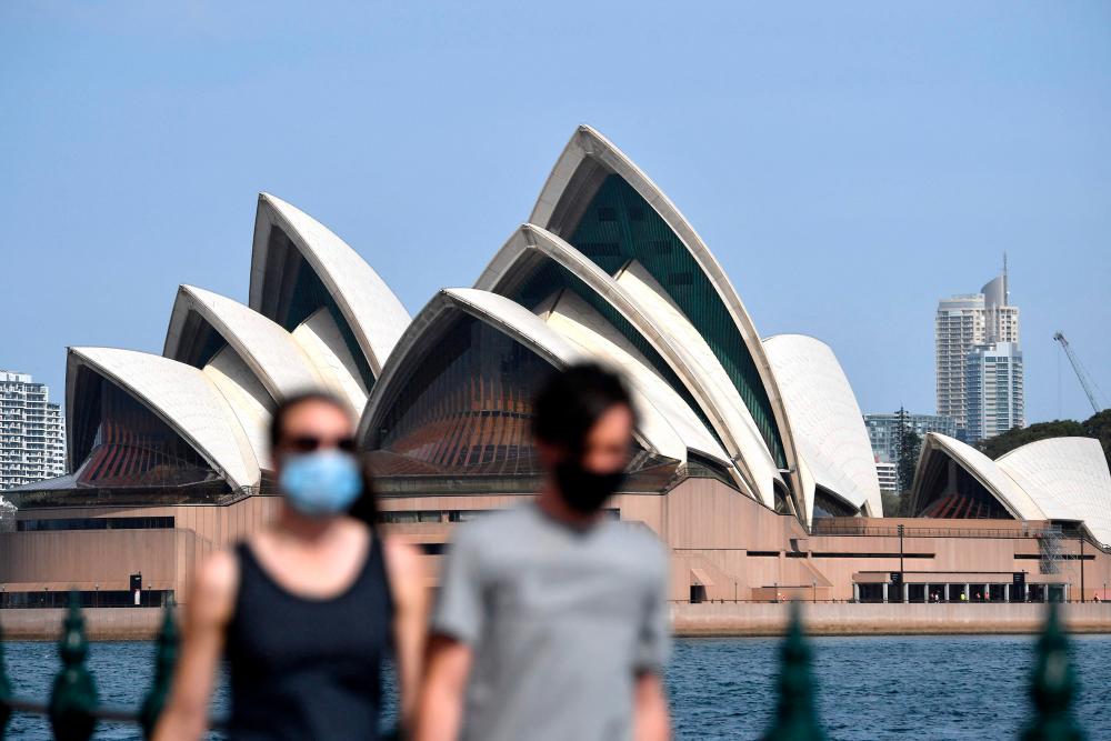 People wearing face masks walk in front of the Opera House in Sydney on September 10, 2021, as New South Wales state recorded 1542 new locally acquired cases of Covid-19 and nine deaths in the past 24 hours. AFPpix