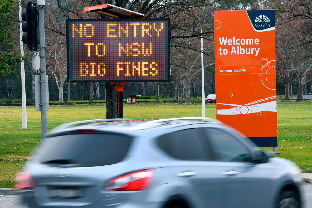 A car passes a sign in the southern New South Wales border city of Albury warning of fines for people entering NSW from Covid-19 coronavirus hotspots in Victoria. A recent spike in coronavirus cases in Melbourne and the closure of the NSW-Victorian state border have cast doubts over Australia's economic recovery efforts.– AFPPIX