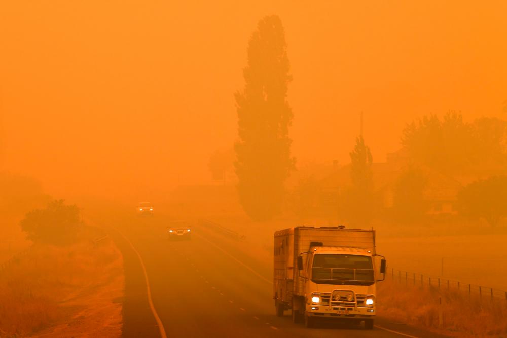 Residents commute on a road through thick smoke from bushfires in Bemboka, in Australia's New South Wales state on January 5, 2020. - AFP