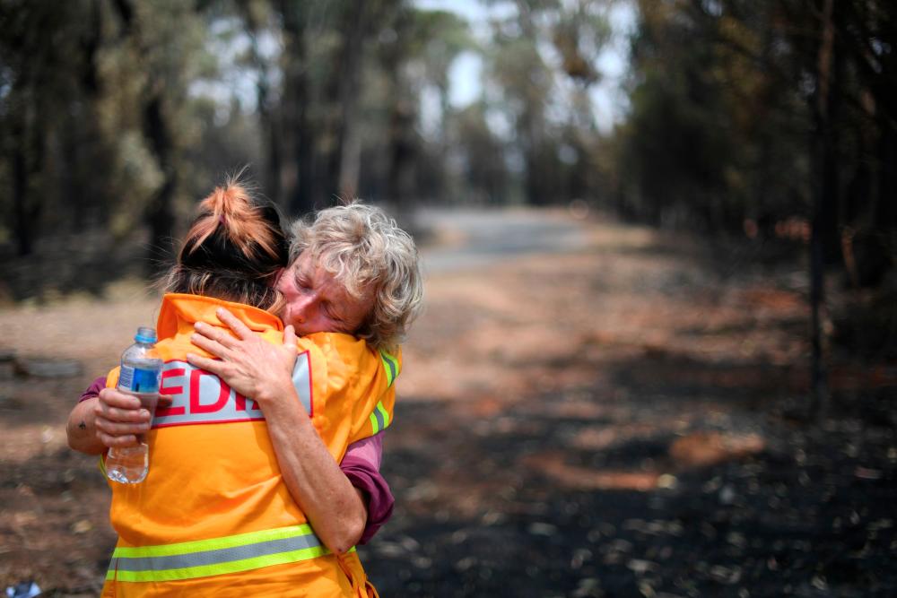 This photo taken on Jan 8, shows 64-year-old orchardist Stephenie Bailey (R) reacting as she describes the impact bushfires have had on her farm in Batlow, in Australia's New South Wales state. — AFP