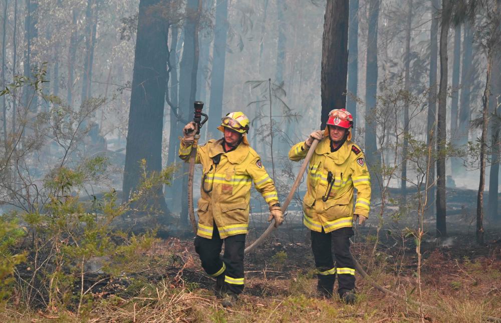 Firefighters look for spot fires in Old Bar, 350km north of Sydney on Nov 11, 2019. — AFP