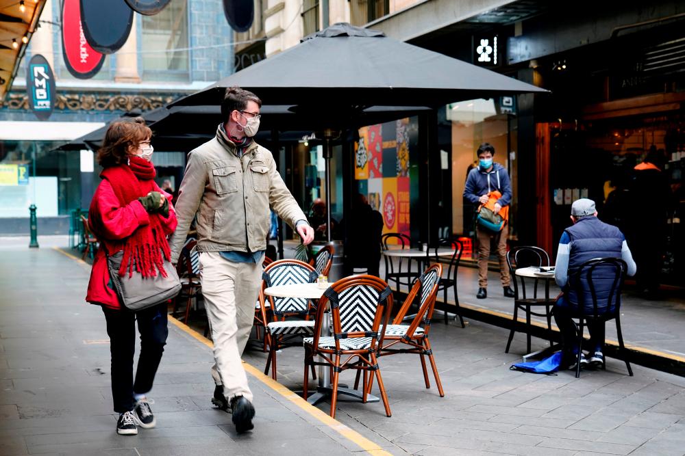 People walk past a cafe after the coronavirus disease (COvid-19) restrictions were eased for the state of Victoria, in Melbourne, Australia, October 28, 2020. — Reuters