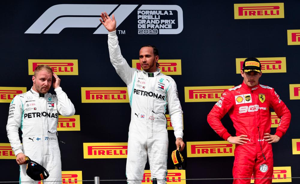 Winner Mercedes' British driver Lewis Hamilton (C) celebrates on the podium next to second placed Mercedes' Finnish driver Valtteri Bottas (L) and third placed Ferrari's Monegasque driver Charles Leclerc (R) after the Formula One Grand Prix de France at the Circuit Paul Ricard in Le Castellet, southern France, on June 23, 2019. — AFP