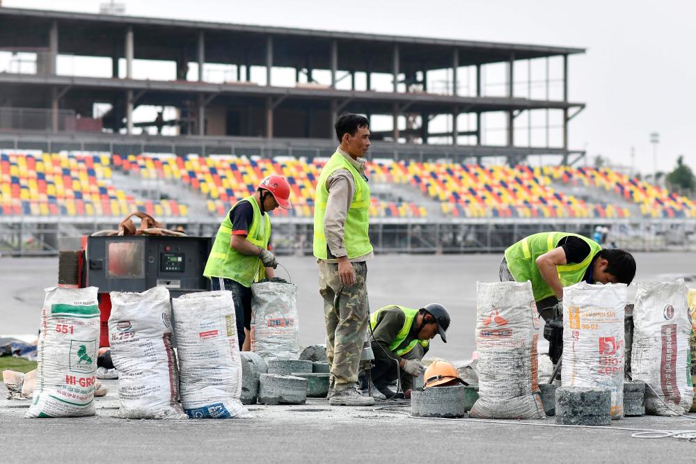 In this file photo taken on February 14, 2020, workers set up a kerb on the track at the under-construction Formula One Vietnam Grand Prix race track site in Hanoi, amid concerns of the Covid-19 coronavirus outbreak. - AFP