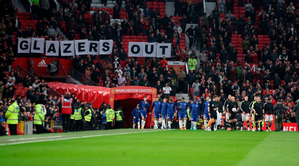 Football - Premier League - Manchester United v Chelsea - Old Trafford, Manchester, Britain - April 28, 2022 The teams walk out as Manchester United fans display banners in protest of the Glazer family’s ownership of the club inside the stadium before the match REUTERSPIX