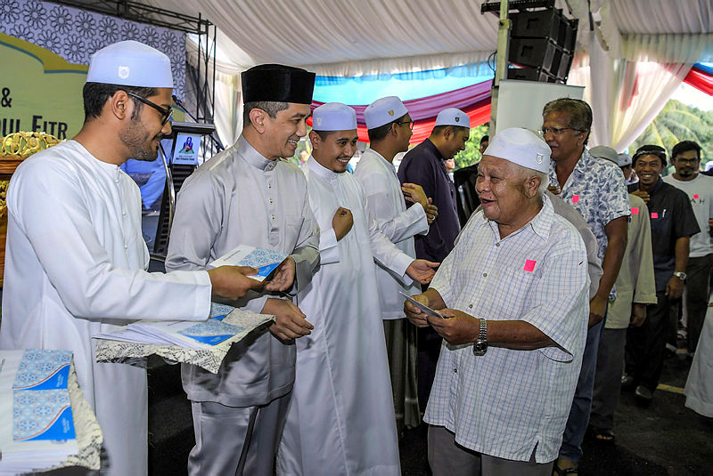 Economic Affairs Minister Datuk Seri Mohamed Azmin Ali (2nd L) hands out aid to senior citizens after the Iftar Perdana Council in the Gombak Setia constituency. — Bernama