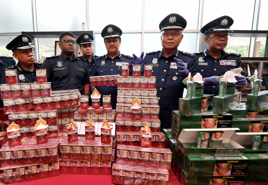 Zulkifli (2R) and officers showing some of the seized cigarettes at a press conference yesterday. — Bernama
