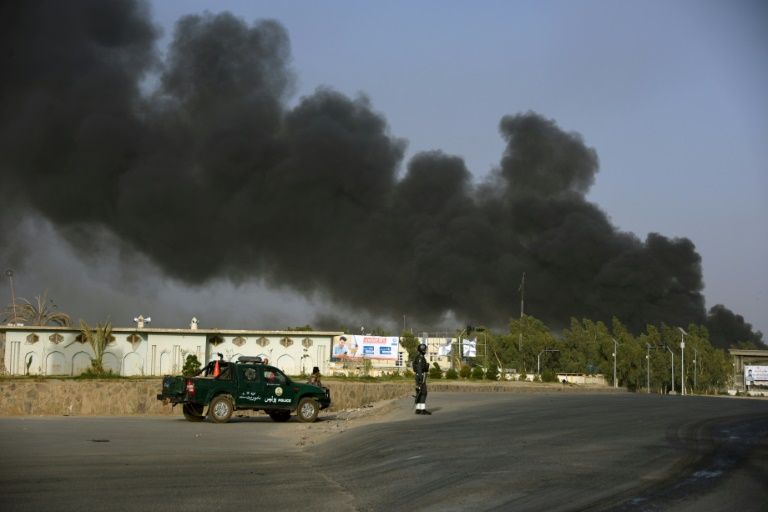 Afghan policemen arrives near a site of car bomb attack as smoke rises from the Police headquarters in Kandahar province. — AFP