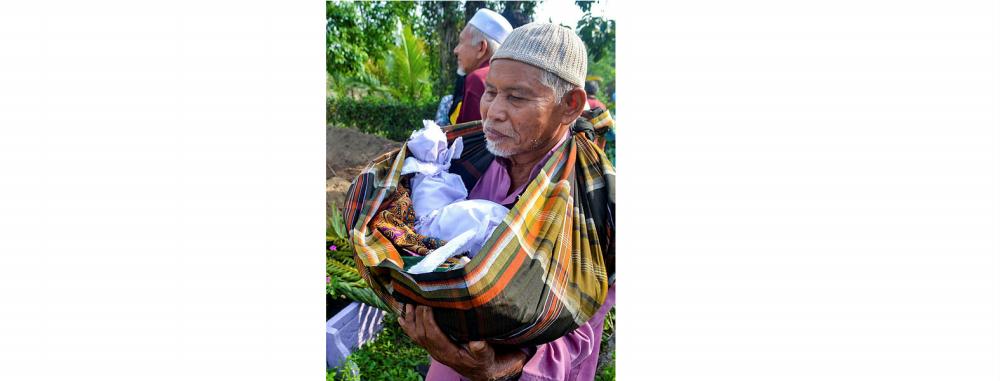 Father of the deceased mother, Wan Ibrahim Awang Kechik, carries the body of his granddaughter to be buried at the Kampung Lembah Muslim cemetery today morning. — Bernama