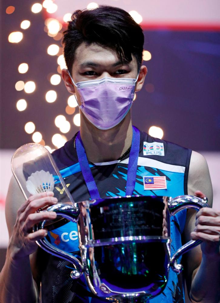 $!Malaysia’s Lee Zii Jia poses on the podium with the winner’s trophy after beating Denmark’s Viktor Axelsen during the men’s singles final on the last day of the All England Open Badminton Championship at the Utilita Arena in Birmingham, central England, on March 21, 2021. / AFP