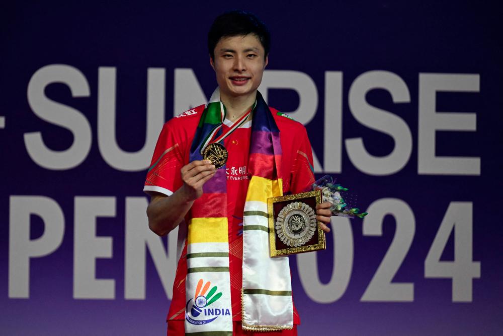 China's Shi Yuqi poses with the trophy after winning against Hong Kong's Lee Cheuk Yiu during men final at India Open badminton tournament held at Indira Gandhi Stadium on January 21, 2024. - AFPPIX