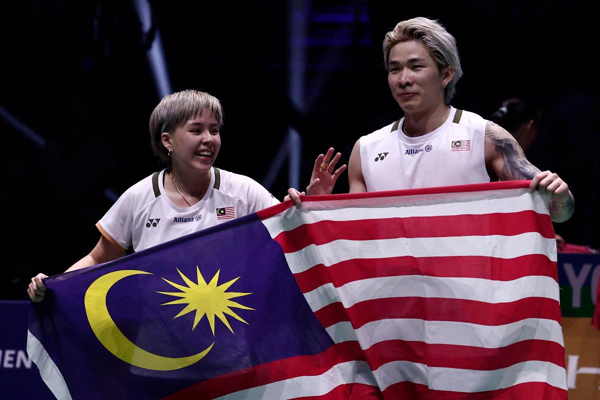Malaysia’s Toh Ee Wei (L) and Chen Tang Jie hold their national flag as they celebrate beating China’s Jiang Zhen Bang and Wei Ya Xin in the mixed doubles final match at the Badminton BWF World Championships at the Adidas Arena in Paris, on August 31, 2025. - Thibaud MORITZ / AFP
