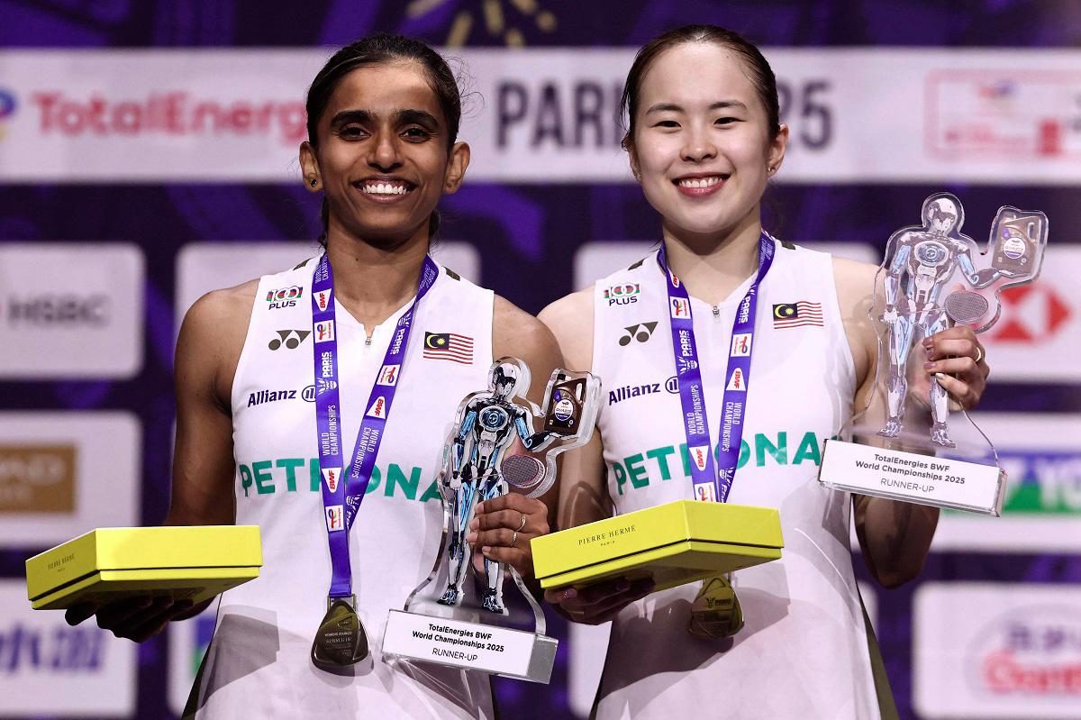 Silver medal winner Malaysia’s Thinaah Muralitharan and Pearly Tan celebrate on podium with their medals and trophies following the women’s doubles final match at the Badminton BWF World Championships at the Adidas Arena in Paris. - AFP pic