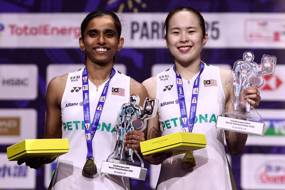 Pemenang pingat perak dari Malaysia, Thinaah Muralitharan dan Pearly Tan, meraikan kejayaan di atas podium bersama pingat dan trofi mereka selepas perlawanan akhir beregu wanita di Kejohanan Badminton Dunia BWF yang berlangsung di Arena Adidas, Paris, pada 31 Ogos 2025. (Foto oleh Thibaud MORITZ / AFP)